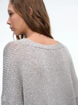 Cardigan de punto con hilo brillante, cuello en V y cierre frontal con botones. Presenta mangas largas con puños acanalados y un diseño de calce holgado.