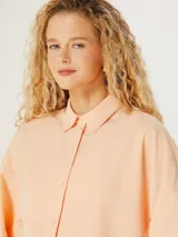 Camisa oversize color naranja con cuello clásico y mangas largas con puños elásticos.