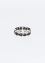 Anillo de acero quirúrgico plateado con una banda central de zirconias y una banda con diseño de guarda griega.