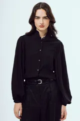 Camisa negra de manga larga abullonada, con cuello mao con volados y cierre frontal con botones.