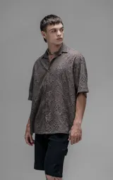 Camisa de manga corta con calce oversize y cuello abierto, confeccionada en algodón con diseño de bordado tipo broderie y efecto de desgaste en el color.
