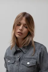 Chaqueta de denim de algodón con corte entallado en la cintura, cuello clásico, cierre frontal con botones metálicos y dos bolsillos con solapa en el pecho.