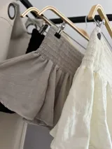 Minifalda de tiro bajo color beige, con cintura elástica fruncida y diseño acampanado con volados.