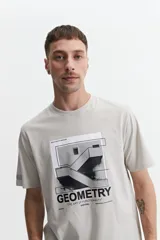 Remera de manga corta color gris claro, con cuello redondo y estampado frontal de estilo arquitectónico/geométrico con texto que incluye la palabra "GEOMETRY".