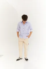 Camisa celeste y blanca a rayas verticales, de corte clásico, con cuello italiano, mangas largas con puños abotonados y logo bordado en el pecho.