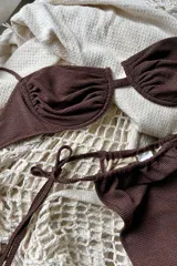 Conjunto de bikini color marrón con lurex, compuesto por un corpiño con aro, breteles regulables y espalda para atar, y una bombacha con tiritas ajustables en los laterales.