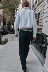 Camisa de popelín color blanco, con cuello solapa, manga larga y bajo abullonado con elástico interior. Cierre frontal con botones.