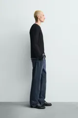 Jersey negro de corte relaxed fit, con estructura de tejido abierto, cuello redondo amplio y manga larga.