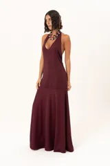 Vestido largo de color bordó, con escote halter profundo y corte a la altura de la cadera con falda amplia.