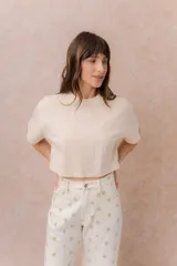Remera crop color beige, de calce amplio, escote redondo y mangas cortas sueltas.
