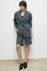 Blazer gris con corte oversize, solapas de muesca, cierre frontal con dos botones, bolsillos con solapa y mangas largas.