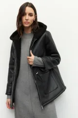 Campera tipo gamulán de cuero sintético negro con interior forrado en corderito sintético. Presenta capucha, cierre frontal con cremallera, bolsillos frontales tipo parche y cordones ajustables en la cintura.