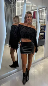 Top tipo capa de un solo hombro, confeccionado en tul negro con diseño floral aterciopelado. Presenta un corte asimétrico y holgado con mangas amplias.