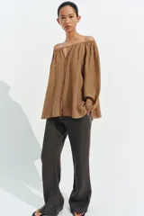 Blusa de lino color blanco, con escote recto ajustable mediante cordón y hombros descubiertos. Cuenta con manga larga abullonada terminada en elástico.