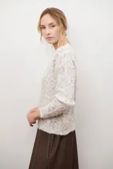 Buzo de punto con cuello redondo, manga larga y textura jaspeada en tonos beige y crema.