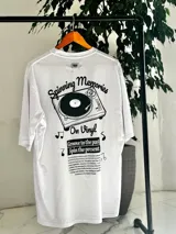 Remera oversize blanca de manga corta, con gran estampado en la espalda de una bandeja de vinilos y texto temático musical.