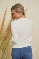 Saco blanco de punto con cuello redondo y detalles de strass en el escote. Tiene mangas largas y cierre frontal con botones.