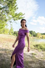 Vestido midi color violeta metalizado, con escote bote drapeado, sin mangas y diseño fluido con pliegues laterales.
