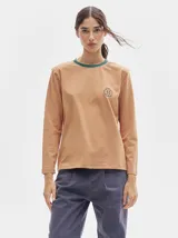 Remera de manga larga con cuello redondo y estampado a rayas horizontales en tonos marrón y negro. Tiene un logo bordado en el pecho de color rojo.