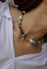 Collar corto de piedras naturales y cuentas multicolor en tonos turquesa, rojo, marrón y beige, con cierre de cadena ajustable.