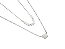 Collar doble de acero plateado con cadena de eslabones cuadrados. El collar más corto tiene dijes de cubos y el más largo tiene un dije cuadrado.