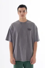 Remera gris con efecto acid wash, corte oversize y estampa en la espalda con personajes de dibujos animados (Bob Esponja, Itchy, Peppa Pig y Bart Simpson) con fajos de billetes.