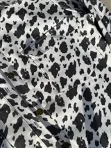 Camisa de denim con estampado de manchas de vaca, corte recto y cierre frontal con botones.