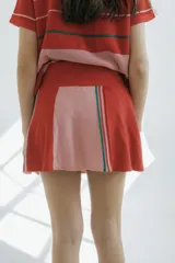 Minifalda de punto a rayas en tonos rojo, rosado y detalles en verde, con cintura elástica con cordón ajustable.