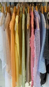 Prenda tipo poncho o chal de tejido de punto muy fino y calado, con efecto arrugado y bordes ondulados. Disponible en una amplia gama de colores pastel y neutros, incluyendo blanco, beige, naranja, amarillo, verde claro, gris, rosa, lila, celeste y negro con brillo.