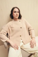 Sweater color beige de tejido de punto con cruce irregular y botones a contraste.