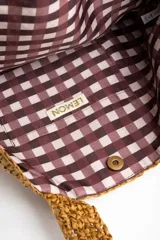 Bolso tipo tote color camel, confeccionado en material trenzado con textura rústica, doble asa de hombro y pequeño aplique metálico con el logo de la marca.
