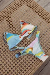 Conjunto de bikini con estampado abstracto multicolor. El top es de estilo triángulo con breteles regulables y cierre de gancho en la espalda. La bombacha es tipo vedetina con laterales fruncidos elásticos.