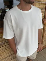 Remera blanca de tejido texturizado con cuello redondo y corte holgado.