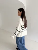 Sweater estilo chomba con cierre frontal, confeccionado en tejido bremer rayado de manga larga. Presenta un diseño amplio y moderno con cuello polo.
