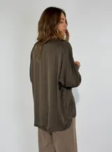 Blusa color beige de mangas largas con puños elásticos y cuello redondo con detalle de puntilla.