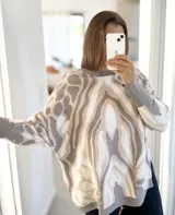 Sweater de punto con diseño abstracto en tonos grises, crudos y beige. Presenta un corte oversize, cuello redondo y terminaciones en tejido acanalado en puños y ruedo.