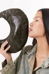 Cartera negra de cuero con forma de medialuna y tachas en zigzag.