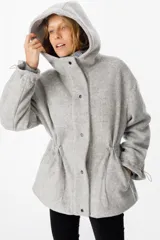 Campera de paño con capucha, cierre frontal con botones a presión y cordones ajustables en la cintura. Presenta un diseño de corte recto con mangas largas y puños ajustables.