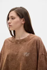 Remera color crudo de algodón lavado, corte cropped y mangas cortas. Presenta un pequeño bordado con las iniciales "PS" en el pecho.