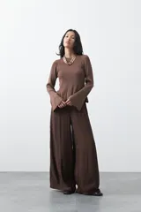 Top de tejido acanalado con sutil acabado metalizado, de silueta entallada con diseño peplum en la cintura y mangas largas levemente acampanadas.