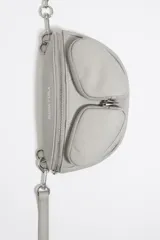 Riñonera de cuero gris con diseño de bolsillos frontales con cierre, correa de cuero ajustable y detalle de cadena metálica decorativa. Cuenta con cierre principal de cremallera y logo estampado en la parte superior.