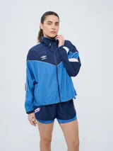 Campera deportiva Umbro del Club Nacional de Football, modelo Sky para mujer. Diseño en tonos azul marino y celeste con detalles en blanco y líneas finas rosadas, cuello alto, cierre frontal y bolsillos.