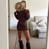 Vestido corto de punto color marrón, con escote tipo bote que deja los hombros al descubierto y mangas largas. El diseño es ajustado al cuerpo.