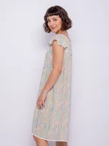 Vestido corto de viscosa con estampado a rayas verticales en tonos celeste, azul y blanco. Sin mangas, con volados en los hombros y escote cuadrado con ribete azul marino.