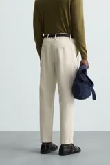 Pantalón chino de algodón color crema, corte regular fit, con cierre frontal de cremallera y botón, bolsillos delanteros y bolsillos traseros de vivo con botón.