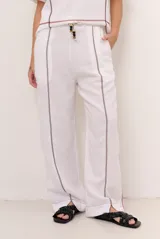 Pantalon de lino color marrón con costuras blancas decorativas a lo largo de las piernas y corte amplio.
