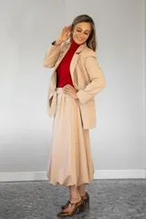 Pollera midi de corte amplio y diseño tipo bomber, con cintura alta y ajuste mediante lazo, confeccionada en tela de color beige.