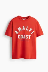 Remera de algodón color rojo con cuello redondo y estampado frontal con la leyenda 'AMALFI COAST' en letras blancas y azules.