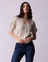 Cárdigan tejido color beige con escote en V, abertura frontal con botones y mangas cortas abullonadas.