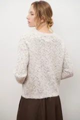 Buzo de punto con cuello redondo, manga larga y textura jaspeada en tonos beige y crema.